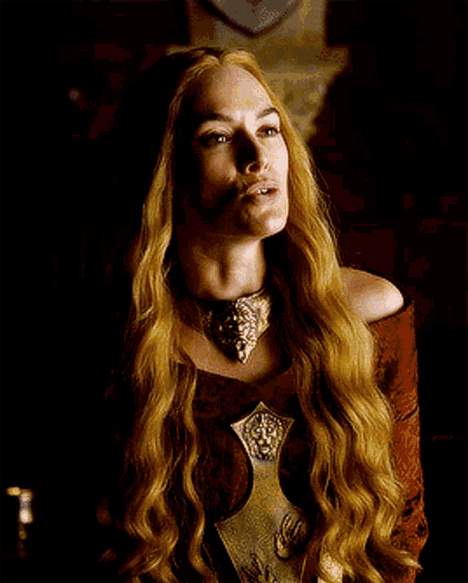 a woman with long blonde hair is wearing a necklace with a lion head on it