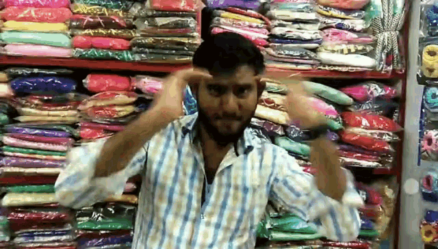 a man in a striped shirt is standing in front of a shelf of clothes