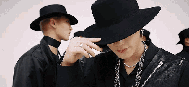 a man wearing a black hat and a necklace covering his face