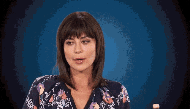 a woman in a floral shirt is making a funny face