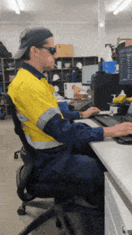 a man in a yellow shirt is typing on a computer