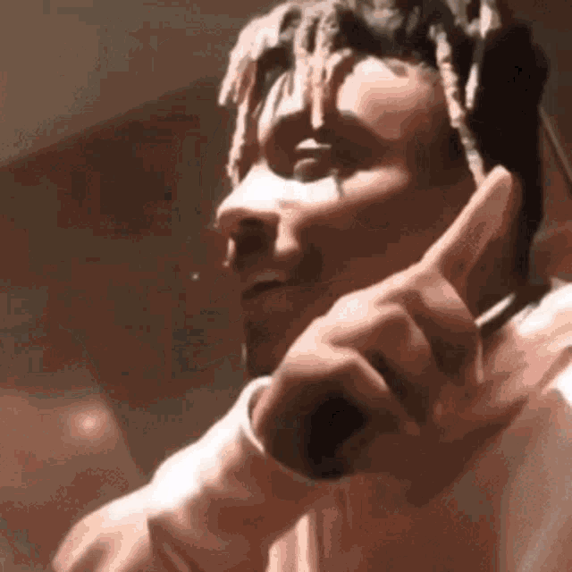 a man with dreadlocks is holding a microphone in his hand and giving a thumbs up .