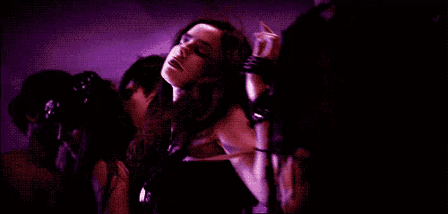 a woman in a black dress is dancing in a crowd