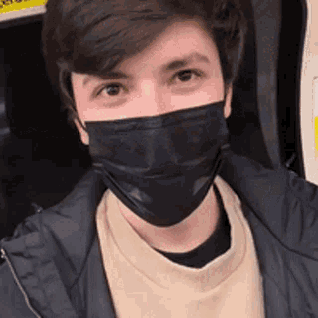 a young man wearing a black face mask on a bus