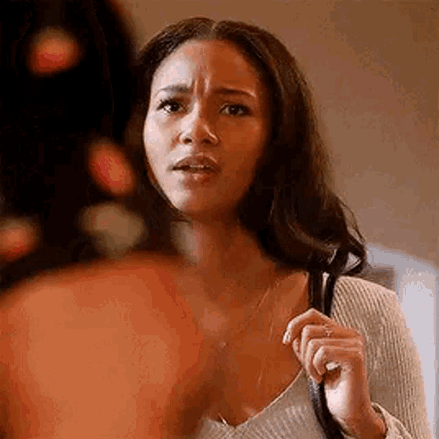 a woman is holding a purse in her hand and looking at another woman .
