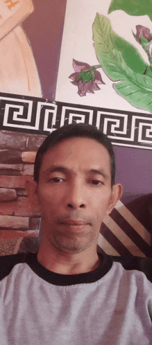 a man taking a selfie in front of a wall with greek key designs
