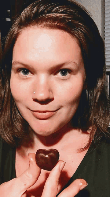 a woman with a nose ring holds a heart shaped chocolate