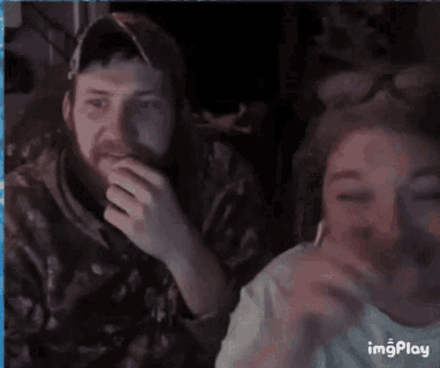 a man and a woman are sitting next to each other on a computer screen and the woman is sticking her tongue out .