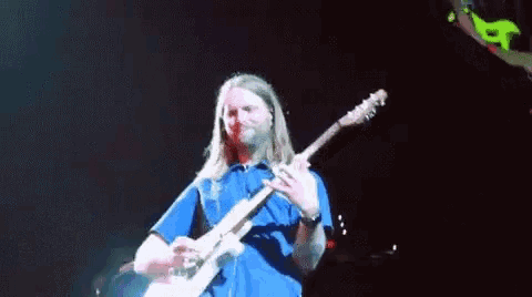 a man with long hair and a beard is playing a guitar on a stage .