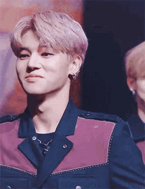 a close up of a person wearing a purple and black jacket and earrings .