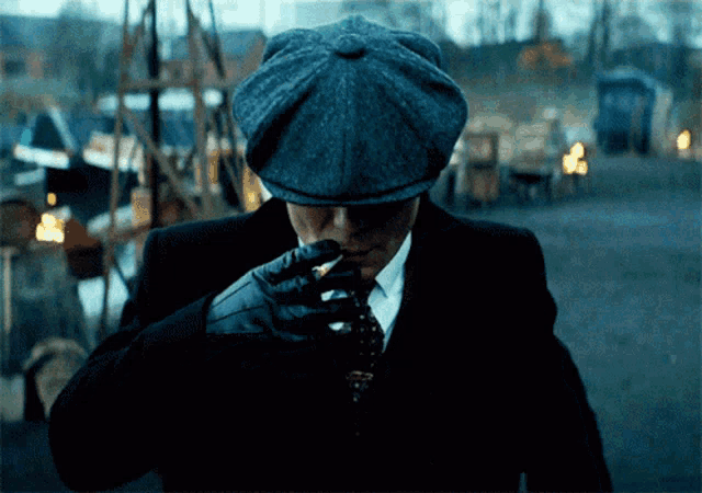 a man in a suit and hat is smoking a cigar