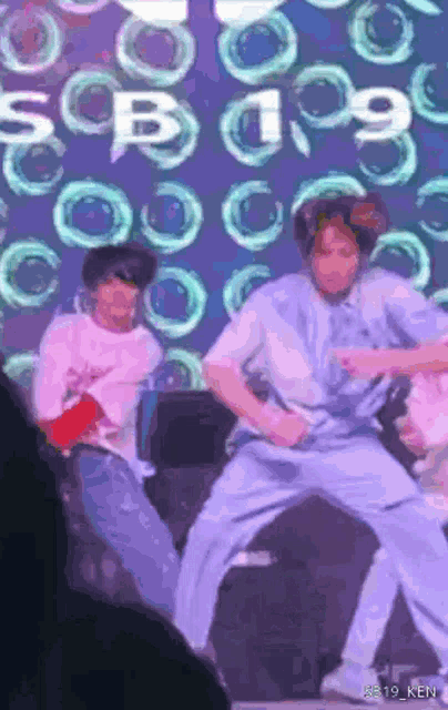 two people are dancing in front of a screen that says sb 19