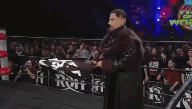 a man in a wrestling ring holds a flag with a skull and crossbones design