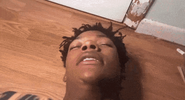 a man is laying on a wooden floor with his eyes closed .