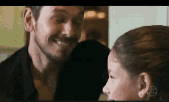 a man and a little girl are smiling at each other and looking at each other .