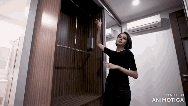 a woman in a black shirt is standing in a room with the words made in animatica on the bottom