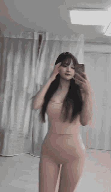 a woman is taking a selfie in front of a mirror in a room .