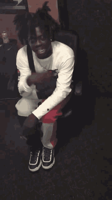 a man wearing a white shirt with a champion logo on it sits on a chair