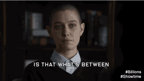 a woman with a shaved head is standing in front of a bookshelf and saying is that what 's between .