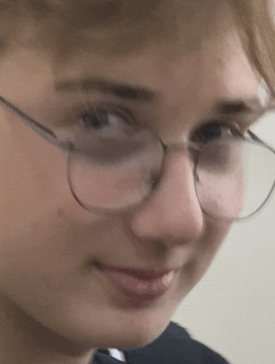 a close up of a young man wearing glasses and making a funny face .