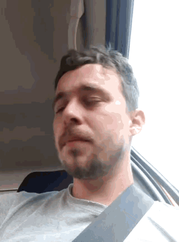 a man with a beard is wearing a seat belt while sitting in a car