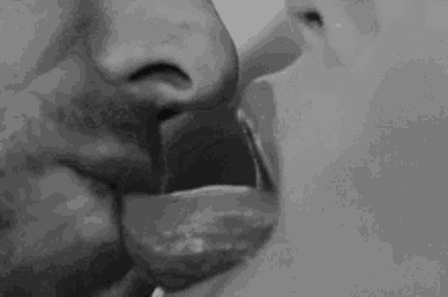 a man and a woman are kissing with their tongues out .