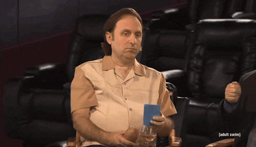 a man sitting in a chair holding a glass and a card that says adult swim on it