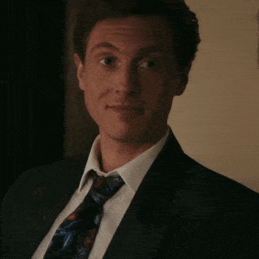 a man in a suit is holding a glass of wine and smiling .