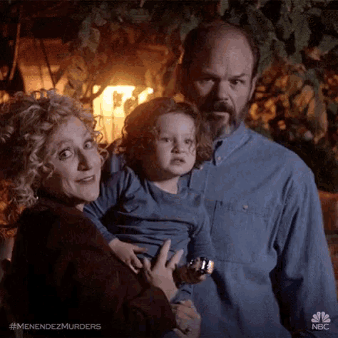 a man and woman are holding a child in their arms .