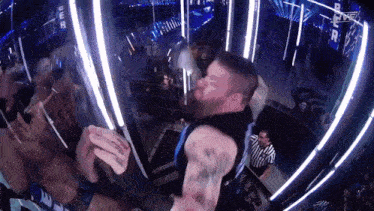 a man with a tattoo on his arm is standing in a dark room with a referee behind him