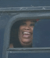a woman is smiling and looking out of a window .