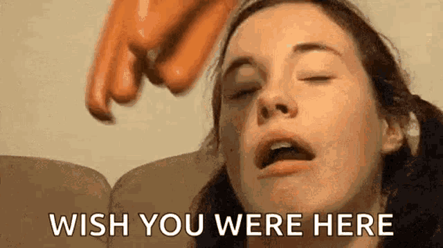 a woman is sitting on a couch with her eyes closed and a person is pointing at her face .