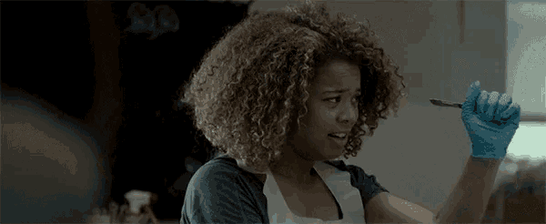 a woman with curly hair is sitting at a table in a dark room .