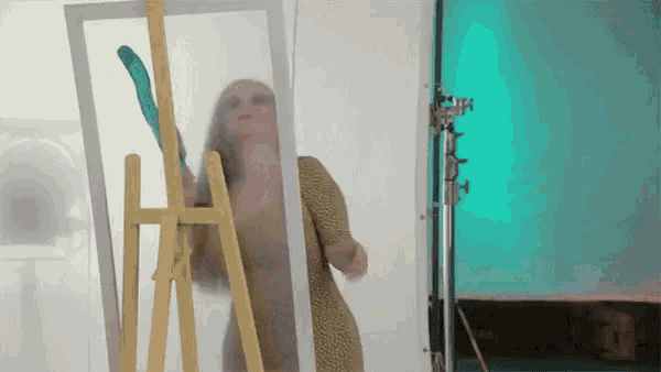 a woman is standing in front of an easel holding a green balloon