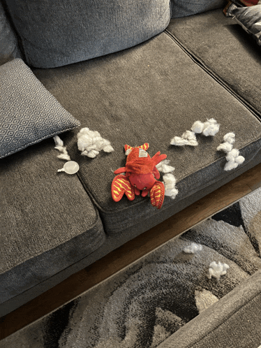 a stuffed animal is sitting on a couch with a lot of cotton balls on it