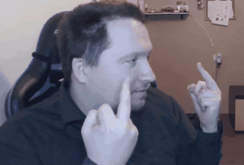 a man in a black shirt is giving the middle finger to the camera