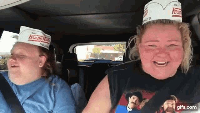two women wearing krispy kreme hats are sitting in a car