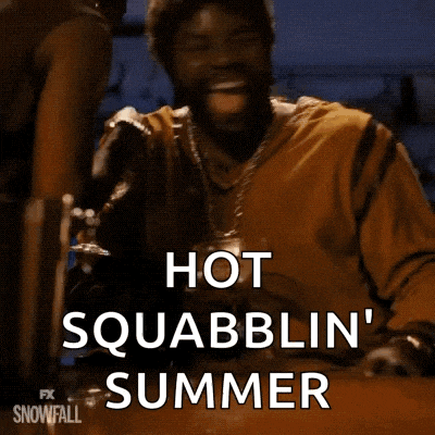 a man is sitting at a table with a glass of beer in his hand and says hot squabblin ' summer .