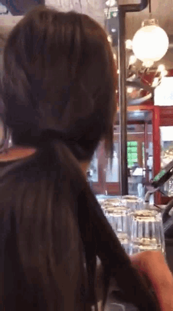 a woman with long hair is standing in front of a bar
