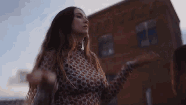a woman is dancing in front of a brick building .