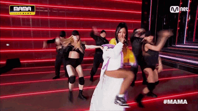 a group of women are dancing on a stage in front of a mnet logo