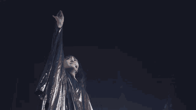 a woman in a black cape is standing in a dark room