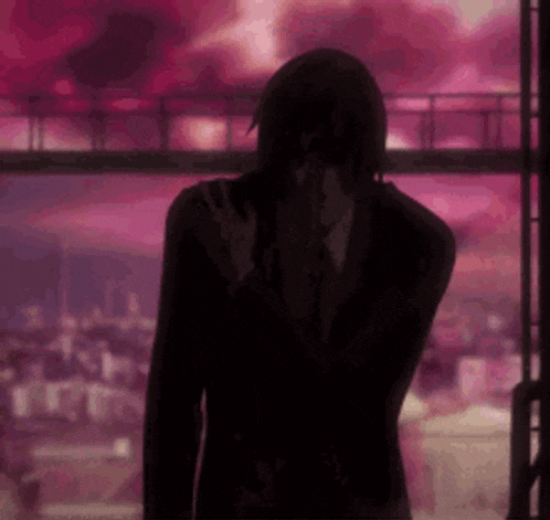 a man in a suit and tie is standing in front of a window with a pink background .