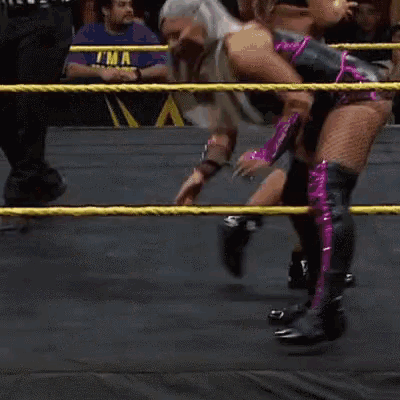 a woman is kneeling down in a wrestling ring with a referee behind her