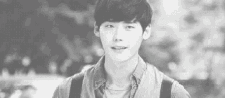 a black and white photo of a young man with a backpack looking at the camera .
