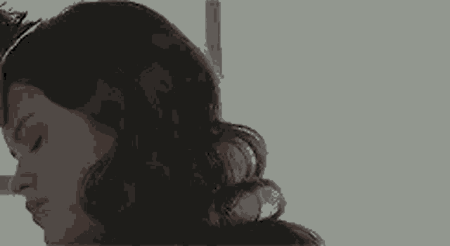 a close up of a woman 's face with her eyes closed and her hand on her head .