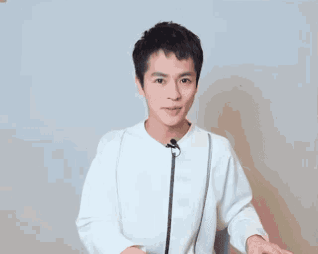 a young man wearing a white sweater with a microphone attached to his neck