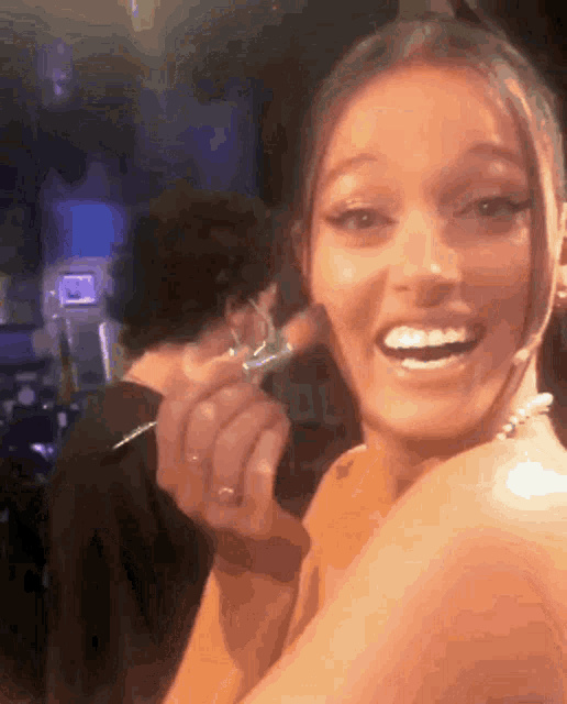 a woman is smiling while holding a ring in her hand