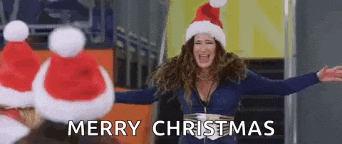 a woman wearing a santa hat is standing in front of a group of santa hats and saying merry christmas .