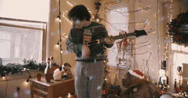 a man in an ugly sweater is playing a guitar in front of a christmas tree